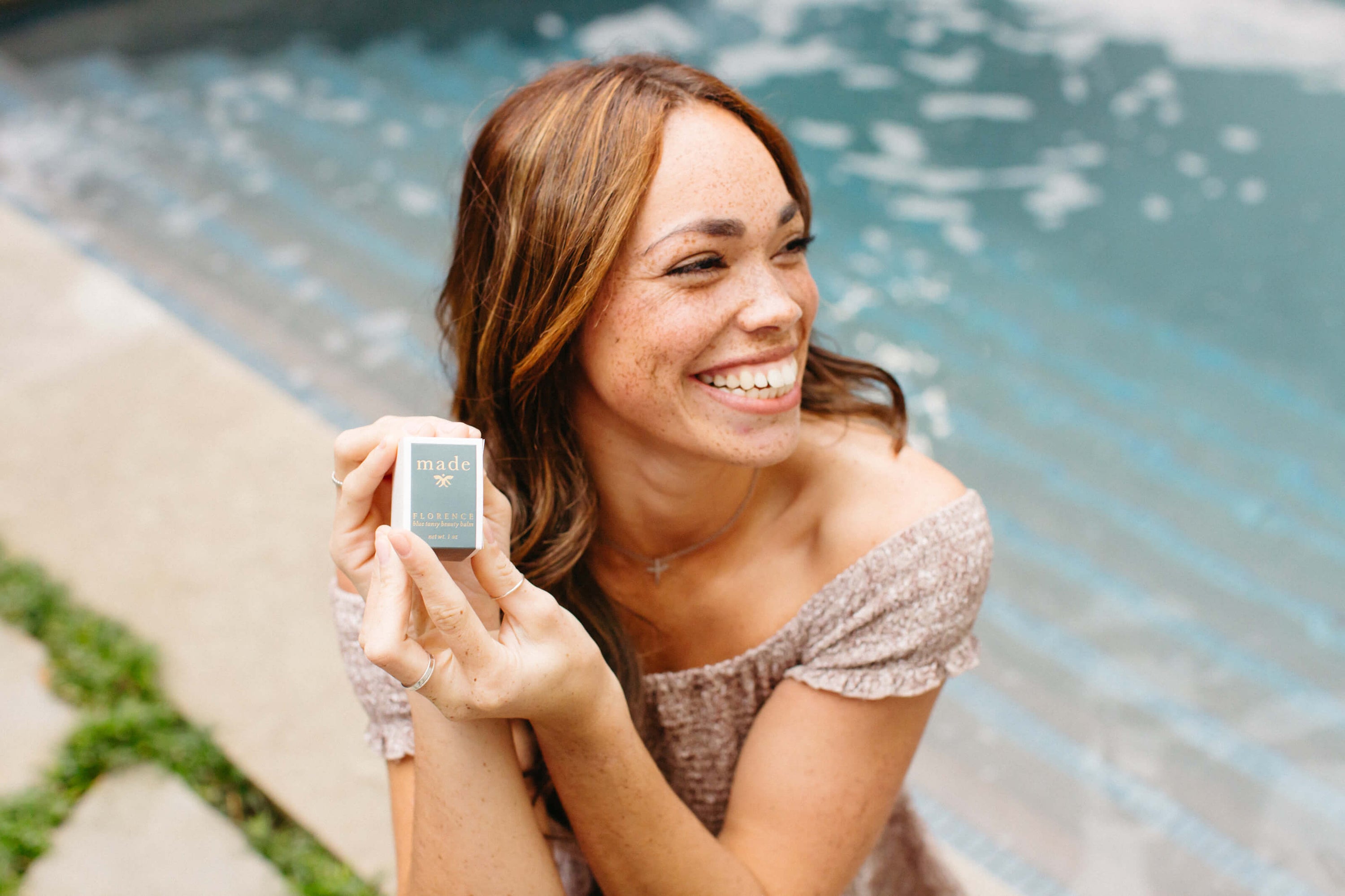 Girl holding blue tansy balm in front of water for Valentine's Day Gift Guide.